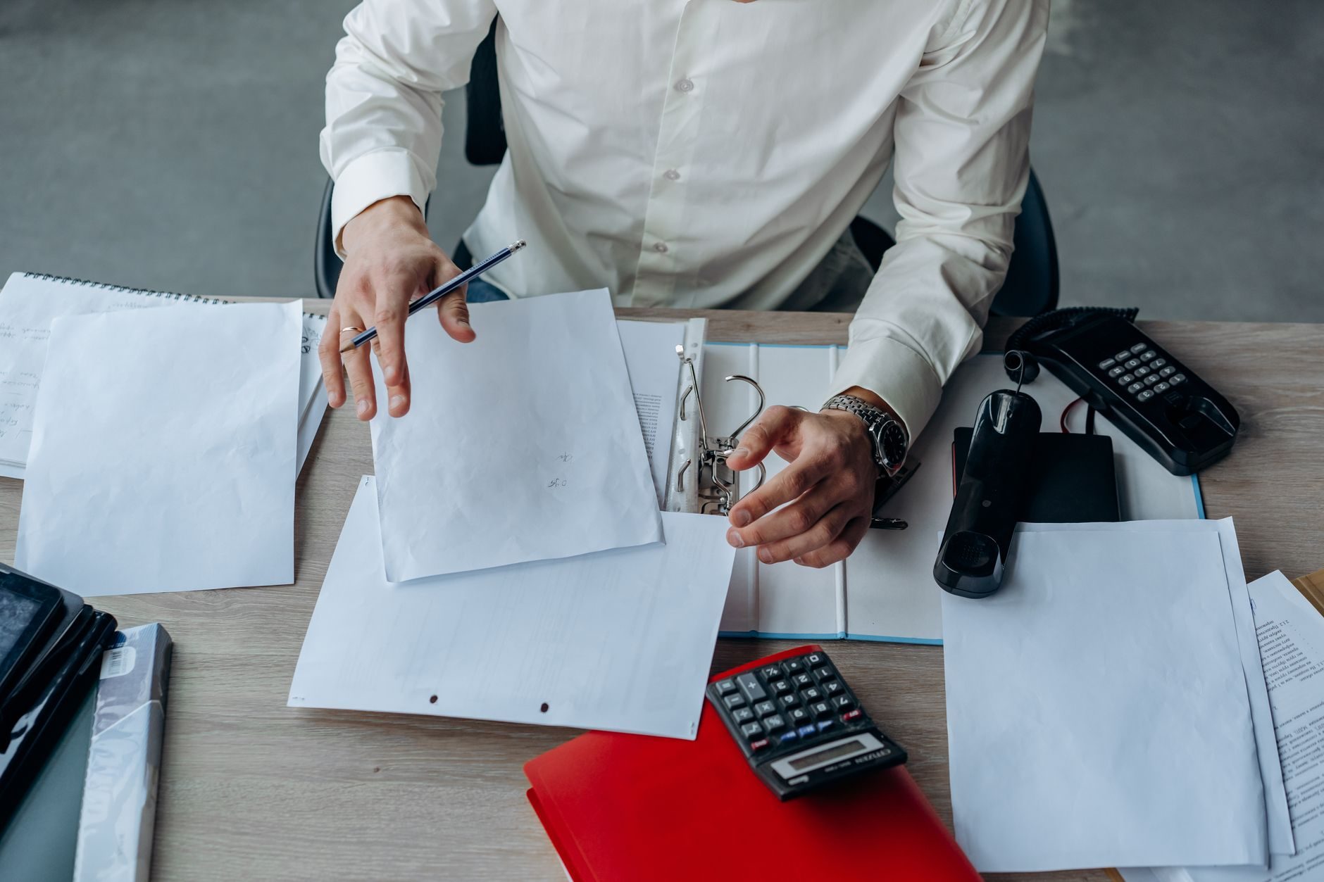 A compliance lead marking up a stack of procedure documents at a desk