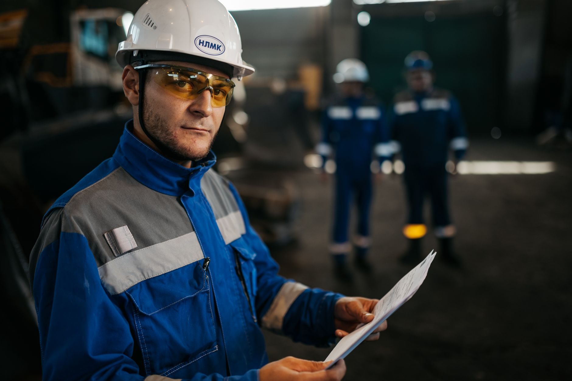 An engineer in a hard hat reviewing a written procedure inside an industrial facility
