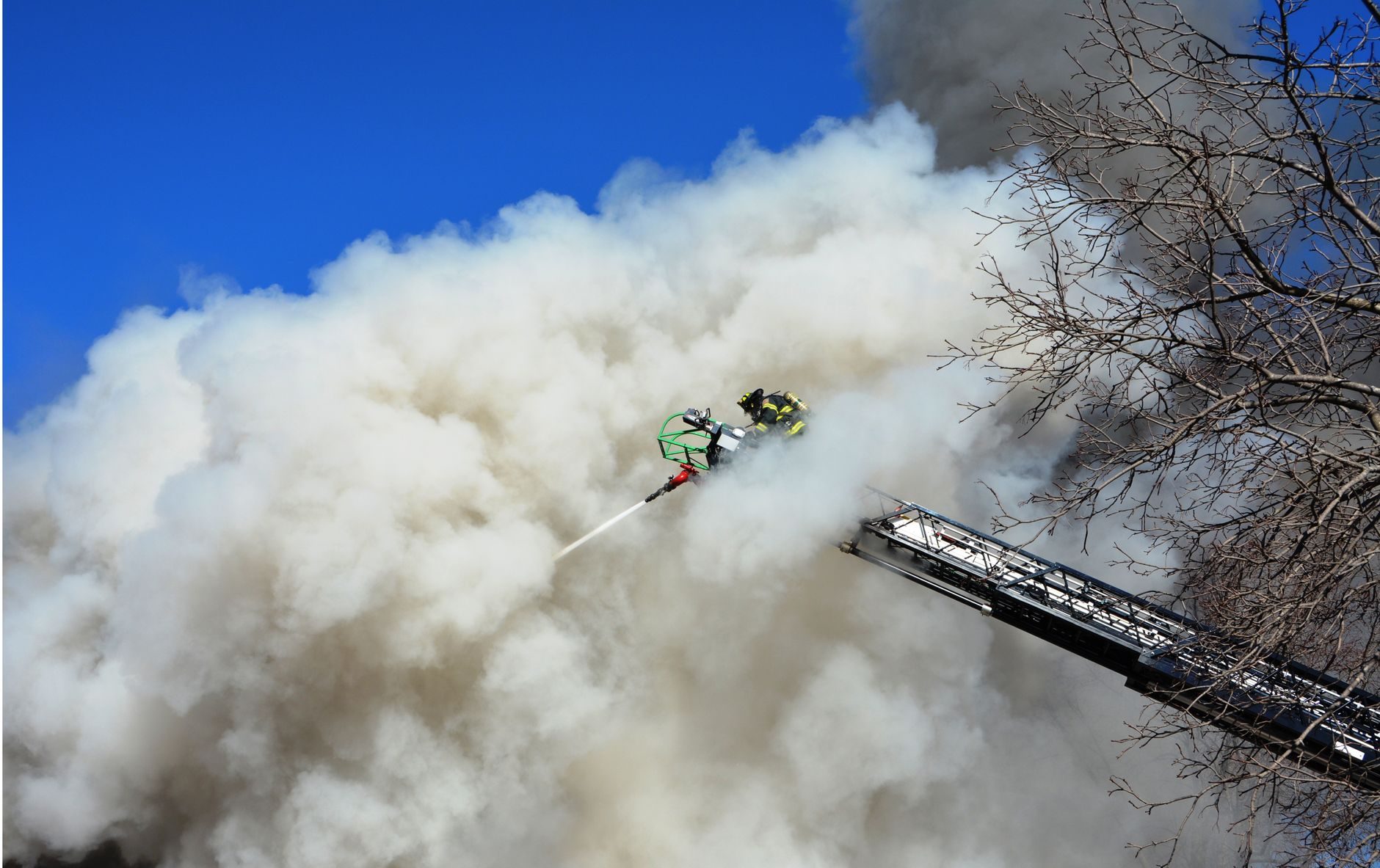 A dense white cloud of smoke or vapor billowing outdoors under a blue sky