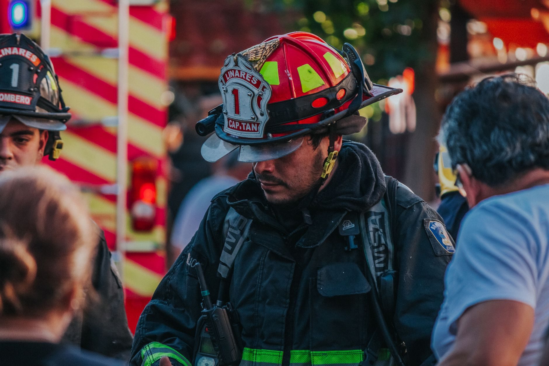 A fire officer in a helmet talking with responders at an incident scene
